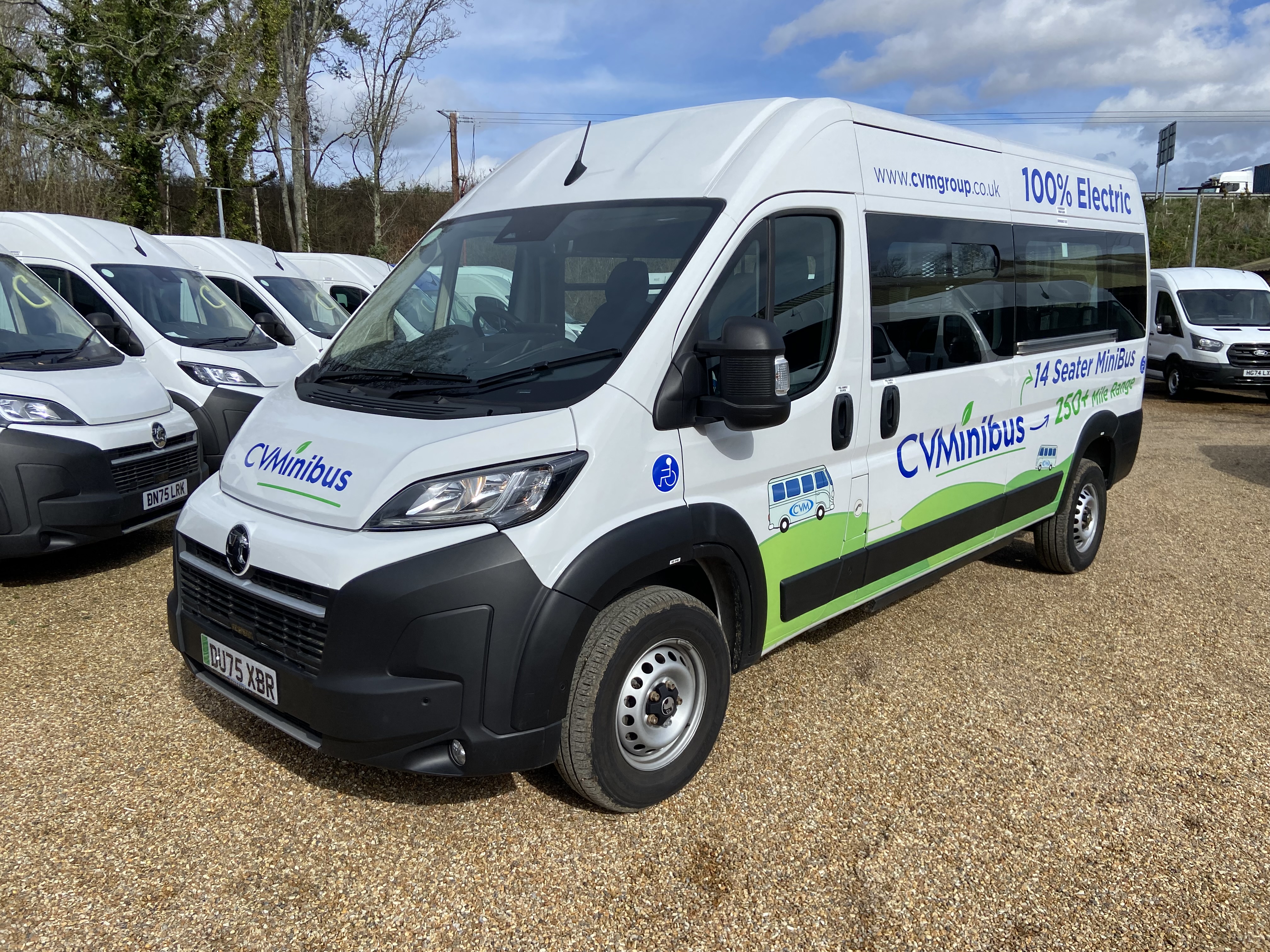 Rear three-quarter view of the 100% electric CVMinibus showing 14 seater and 250+ mile range branding